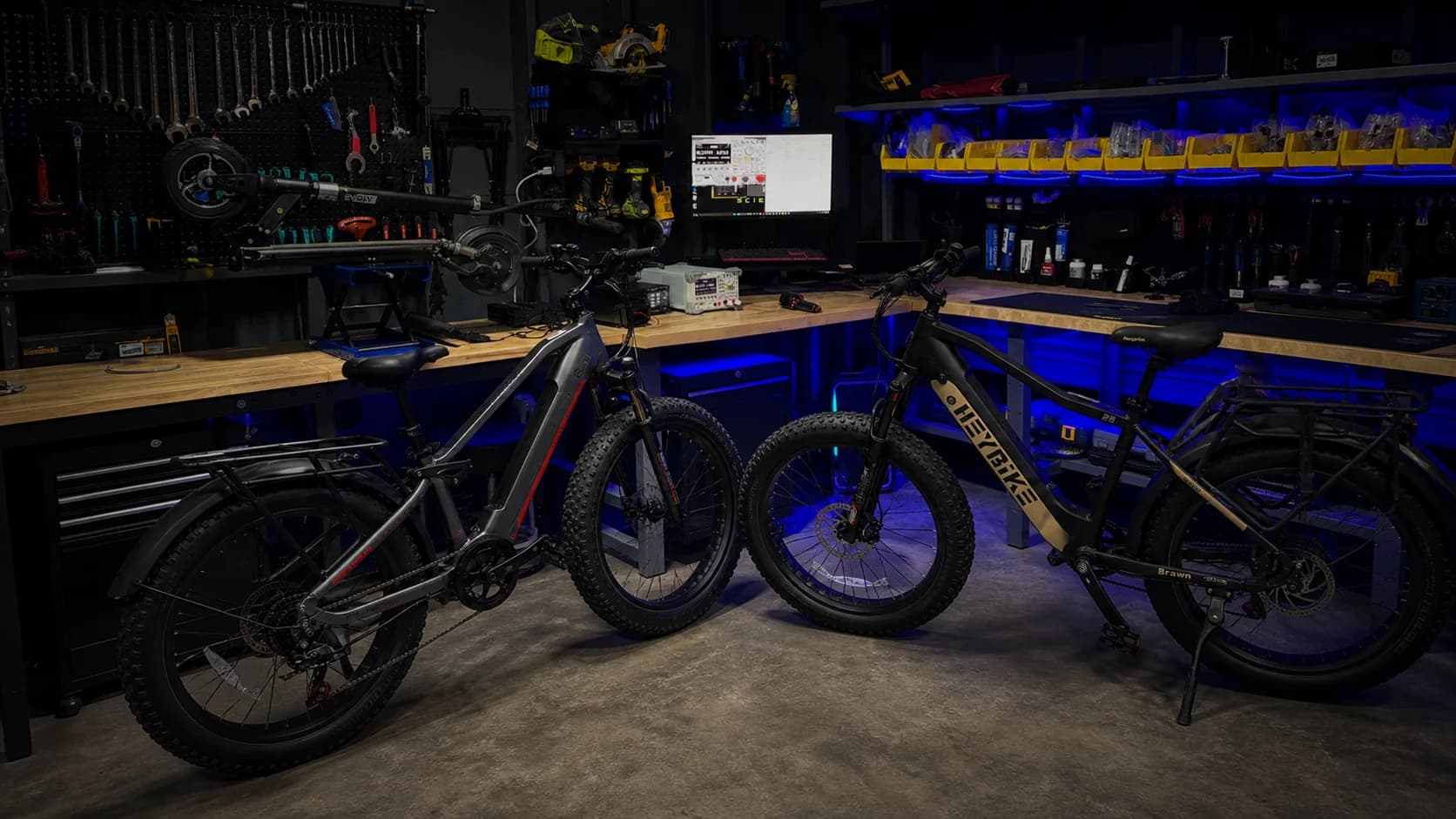 Two e-bikes inside the current Sprocket Science workshop with diagnostic equipment and an electric scooter on the service lift